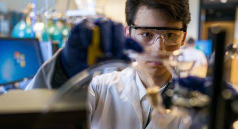 Student pouring liquid into chemical flask