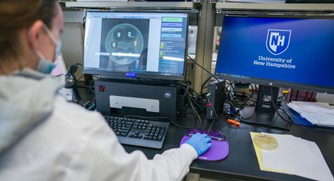 Researcher in a medical mask entering data into a computer